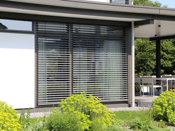 Aussenraffstore als Sonnenschutz an der Fensterfront eines modernen Hauses